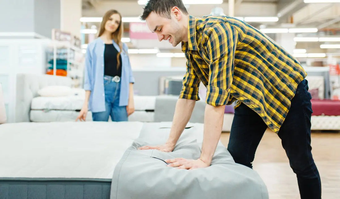 Άντρας δοκιμάζει στρώμα σε κατάστημα επίπλων ενώ γυναίκα παρακολουθεί