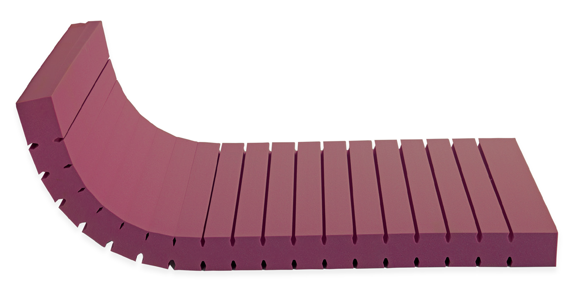 EN59 Medical Foam Flexible — Ροζ αφρώδης πυρήνας με εγκάρσιες εγκοπές, ανασηκωμένος και λυγισμένος στο ένα άκρο. Συνολική αίσθηση: μέτρια.